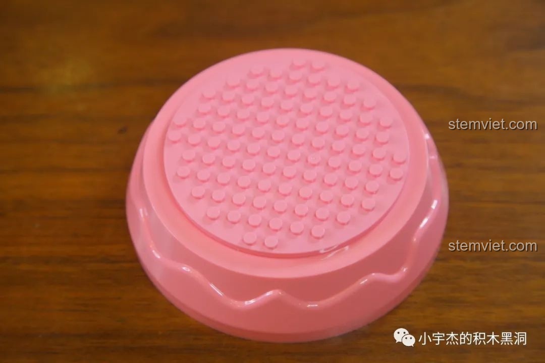 Phần đế nhựa màu hồng của hộp nhạc WOMA C0361, có bề mặt trên là plate tròn để gắn các mảnh ghép.