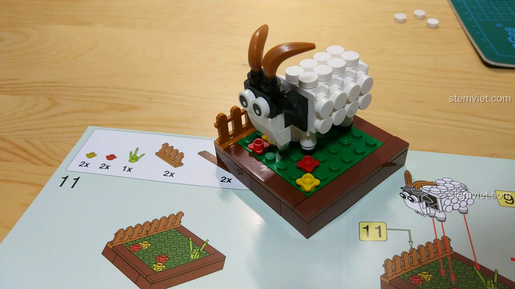 Mô hình Dê Mùi đặt trên cuốn sách hướng dẫn lắp ráp, cho thấy các bước và chi tiết mảnh ghép.