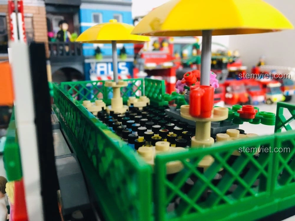 Khu vực bàn ghế ngoài trời có ô che nắng trên mô hình Cửa hàng tiện lợi 7-Eleven SEMBO 601017, tạo không gian sống động.