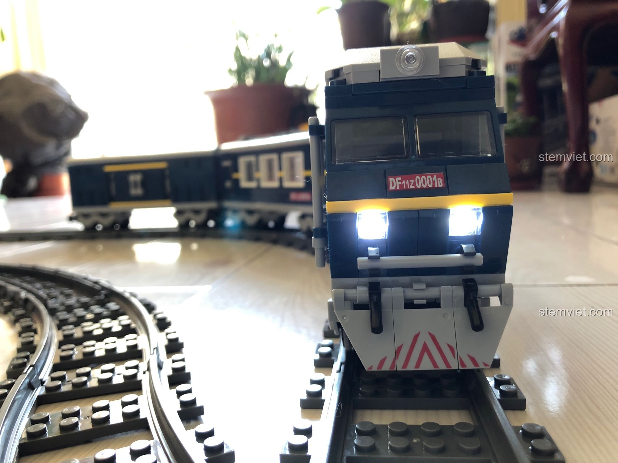 Đầu máy của bộ KAZI 98220 Tàu Hỏa Đông Phong 11Z đang chạy thẳng trên đường ray, đèn pha rực sáng.