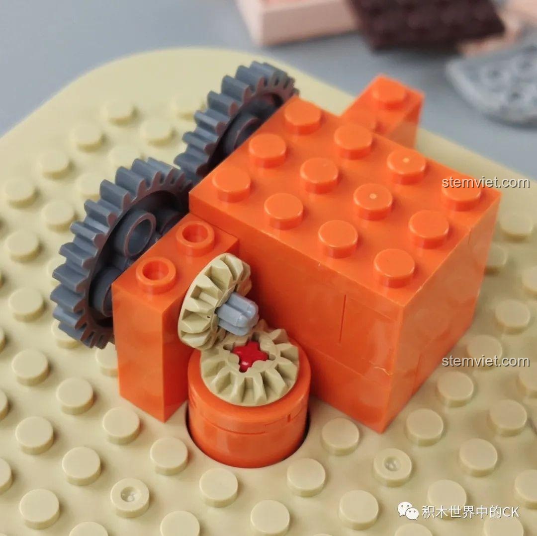 Cận cảnh cơ chế bánh răng bên trong đế hộp nhạc của bộ đồ chơi lắp ráp Hộp nhạc thịt bò viên JAKI JK1801 đang được lắp ráp.