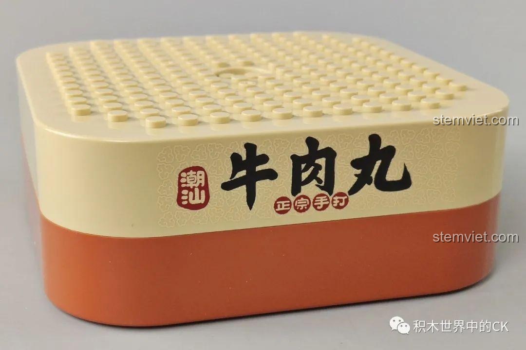 Cận cảnh đế hộp nhạc của bộ đồ chơi lắp ráp Hộp nhạc thịt bò viên JAKI JK1801, với logo và tên sản phẩm được in rõ.