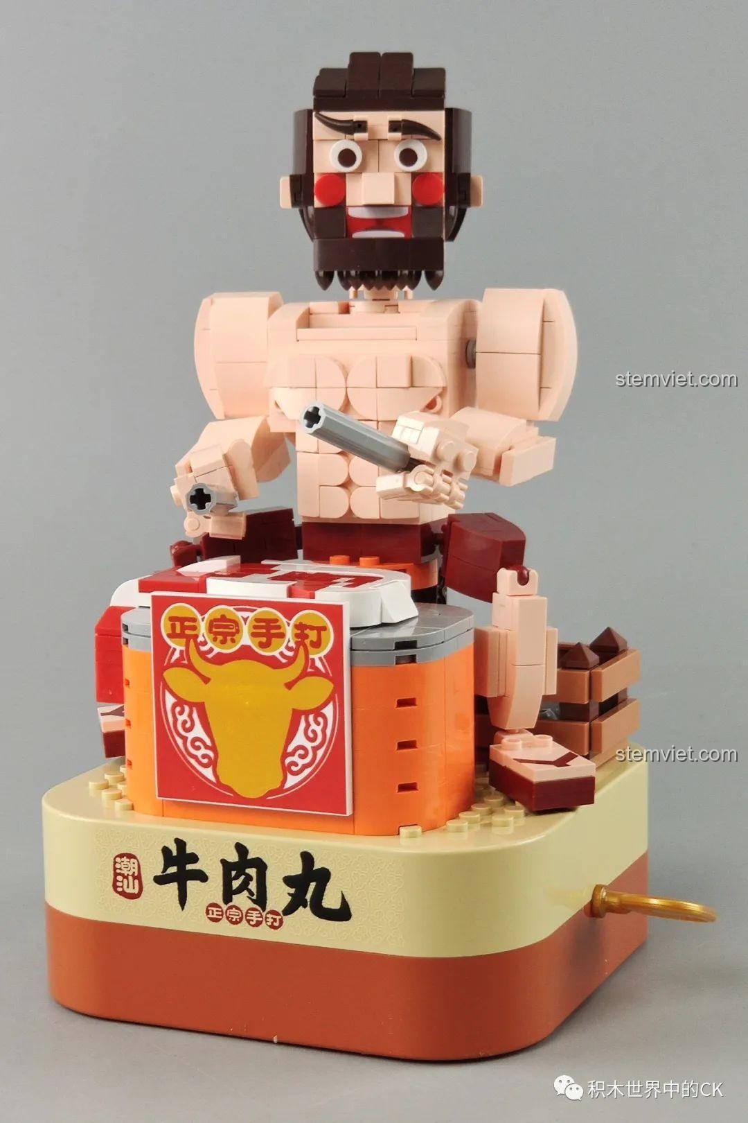Góc chụp cận cảnh mô hình Hộp nhạc thịt bò viên JAKI JK1801 đã hoàn thành, nổi bật chi tiết người đàn ông và thùng thịt.