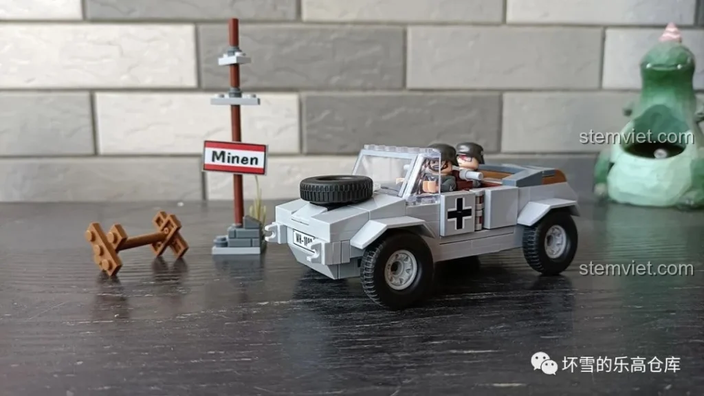 Mô hình đồ chơi lắp ráp xe quân sự Đức QUANGUAN VW82 Kübelwagen màu xám với biển báo "Minen" và hàng rào gỗ, kèm 2 lính.