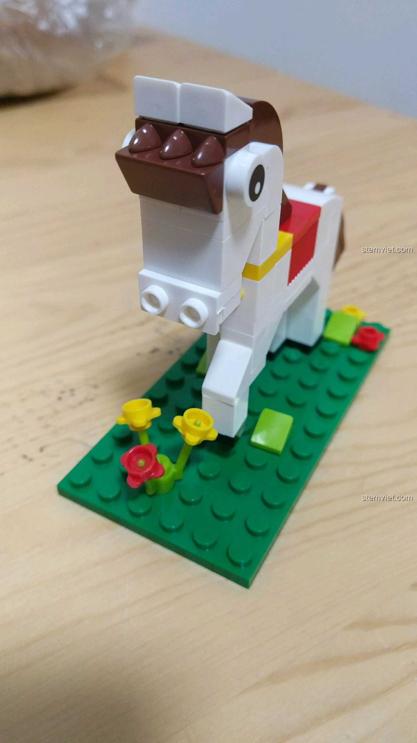 Mô hình Ngựa Ngọ nhìn từ phía trước, cho thấy chi tiết khuôn mặt với đôi mắt và lỗ mũi, đứng trên nền cỏ xanh.