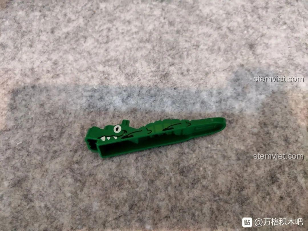 Dụng cụ gỡ mảnh ghép hình con cá sấu màu xanh lá cây đi kèm trong bộ lắp ráp Sluban M38-B0698.