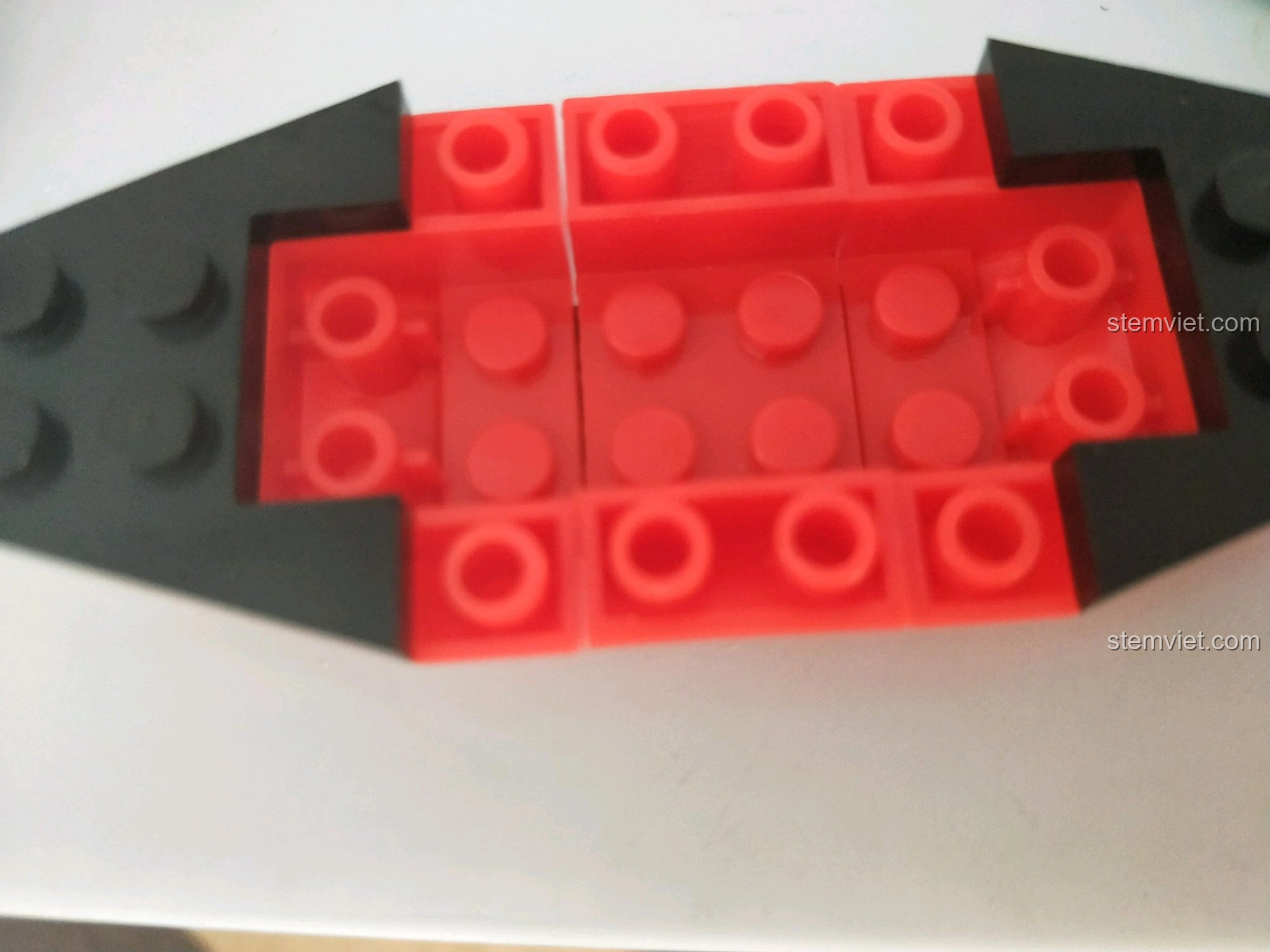 Các chi tiết gạch đỏ và đen tạo thành phần đế của thuyền trong bộ lắp ráp Enlighten 9815 Thuyền Hải Tặc Corsair, thể hiện quá trình lắp ráp.