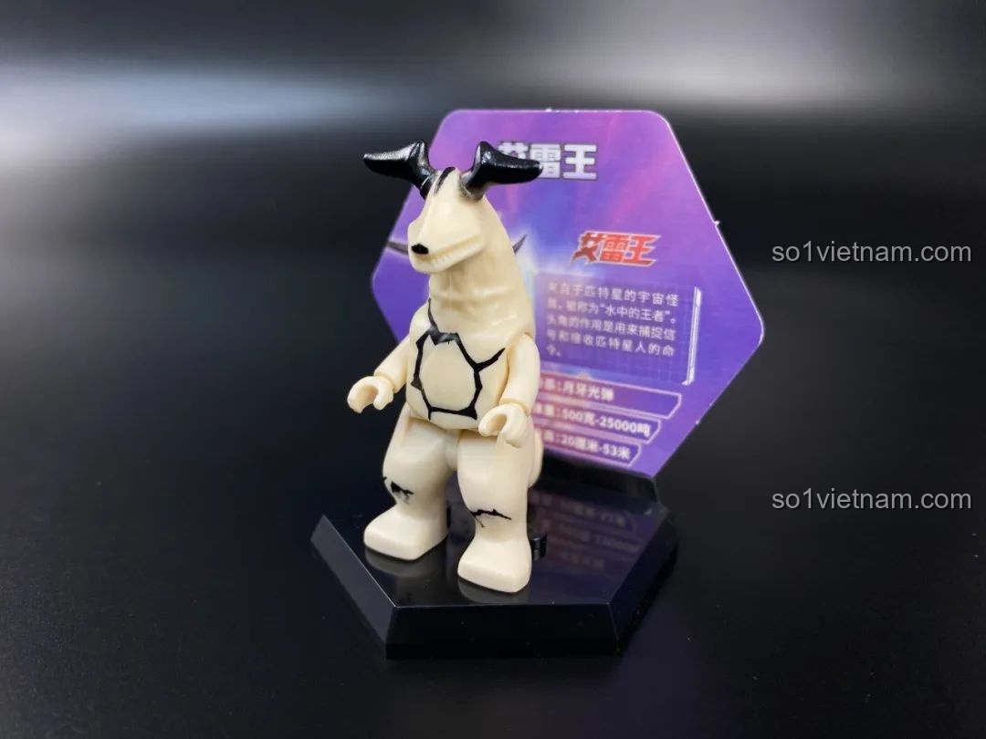 Figure quái vật Red King được đặt trên đế trưng bày hình lục giác với thẻ bài phía sau.