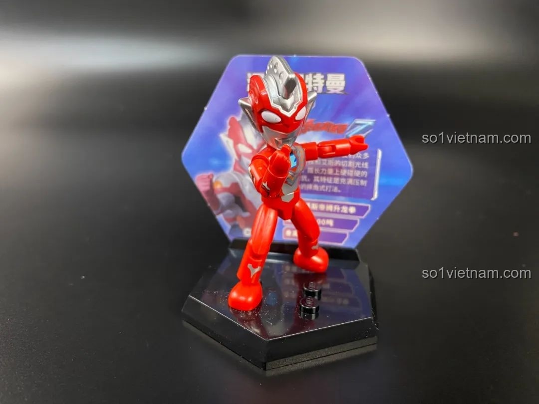 Figure Ultraman Geed Primitive được đặt trên đế trưng bày hình lục giác với thẻ bài phía sau.