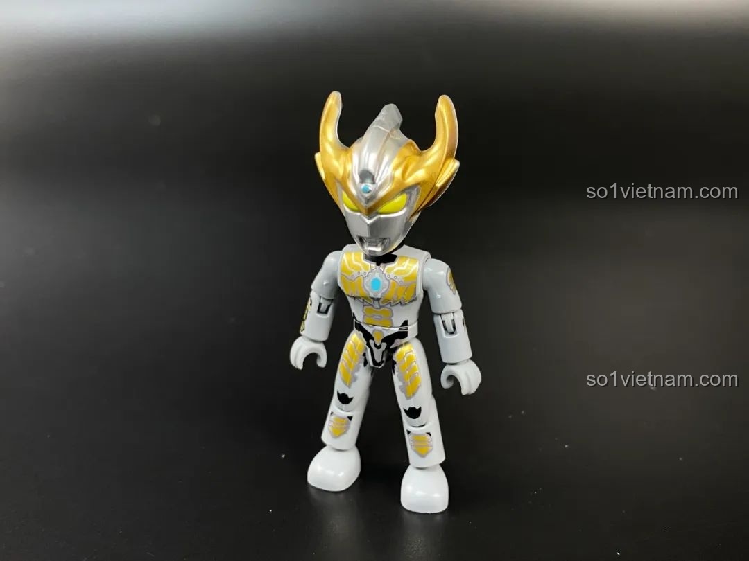 Figure Ultraman Taiga Tri-Strium từ series blind box, với các chi tiết màu vàng và bạc.