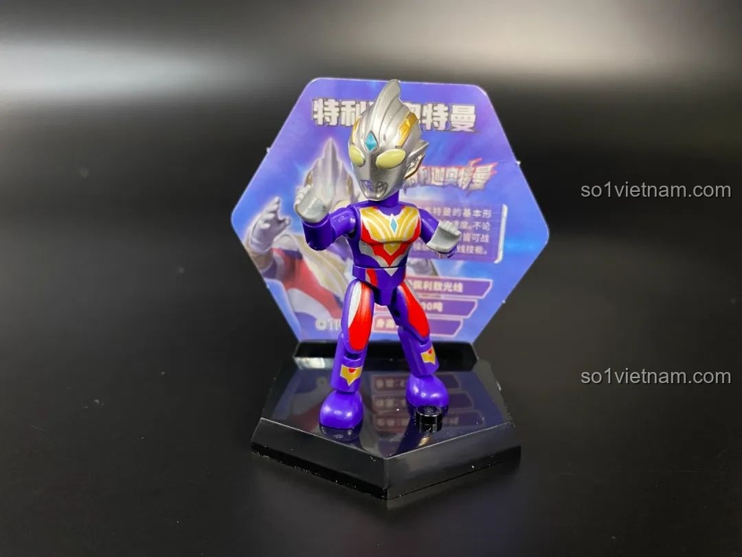 Figure Ultraman Tiga Multi Type được đặt trên đế trưng bày hình lục giác với thẻ bài phía sau.