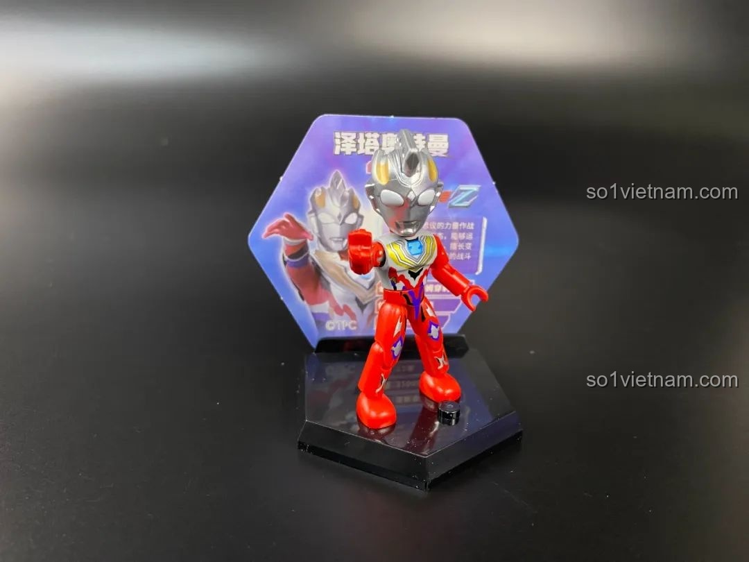 Figure Ultraman Zeta Alpha Edge được đặt trên đế trưng bày hình lục giác với thẻ bài phía sau.