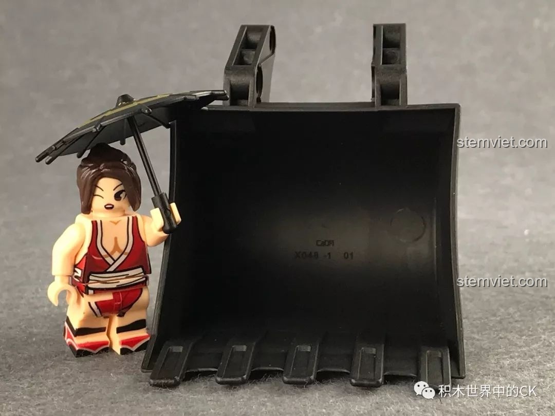 So sánh kích thước gàu xúc của bộ CaDA C51057 với một nhân vật nhỏ, cho thấy sự hoành tráng của chi tiết.