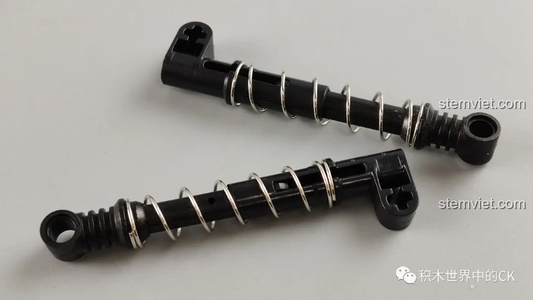 Cận cảnh hai chi tiết giảm xóc với lò xo kim loại của bộ lắp ráp Mould King 13124, thể hiện sự chắc chắn.