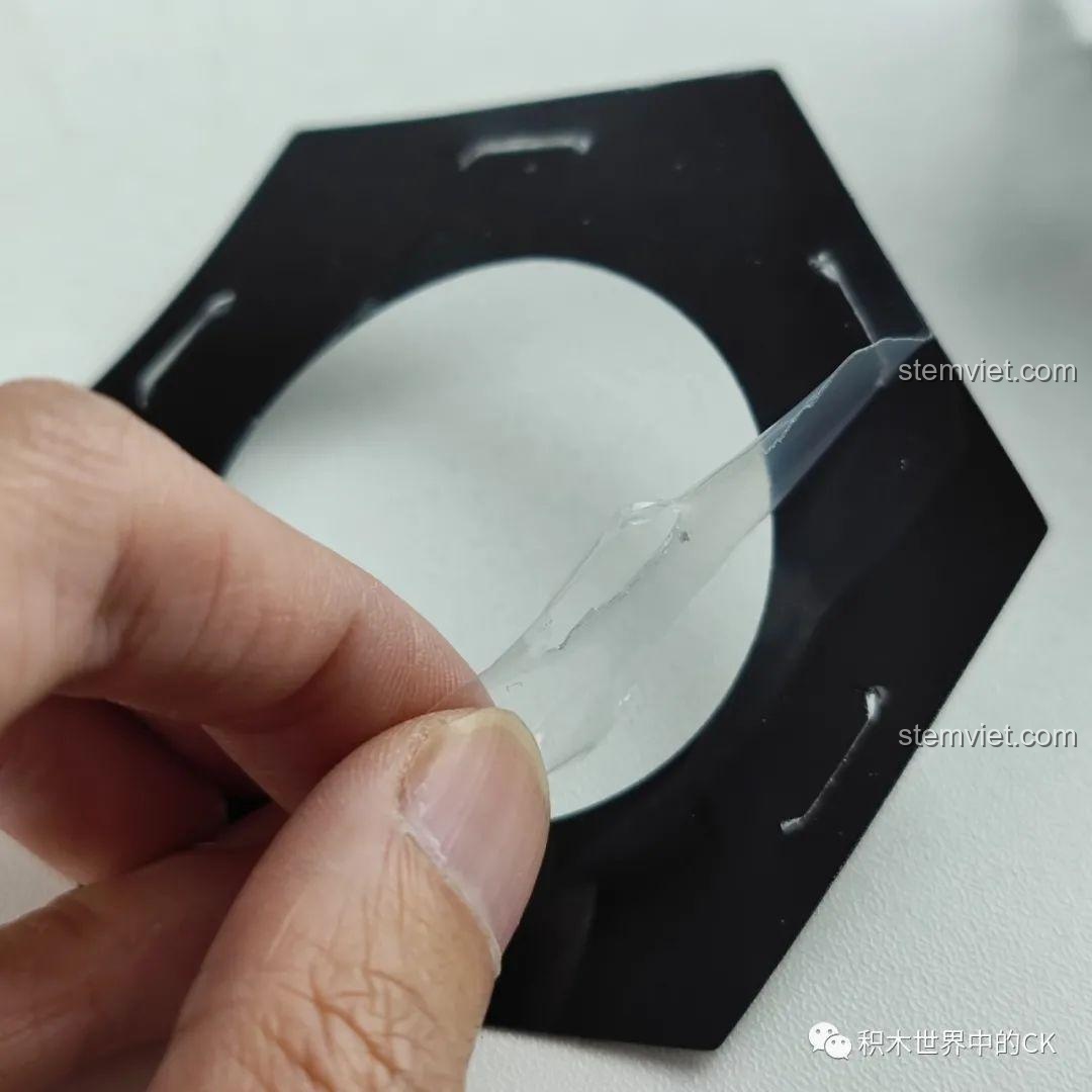 Gỡ lớp màng bảo vệ trên mảnh ghép trong suốt của Hộp nhạc thông minh Công viên giải trí ánh sao JAKI JK1366, chuẩn bị lắp ráp. Trải nghiệm JAKI JK1366 Mô hình hộp nhạc tinh tú.