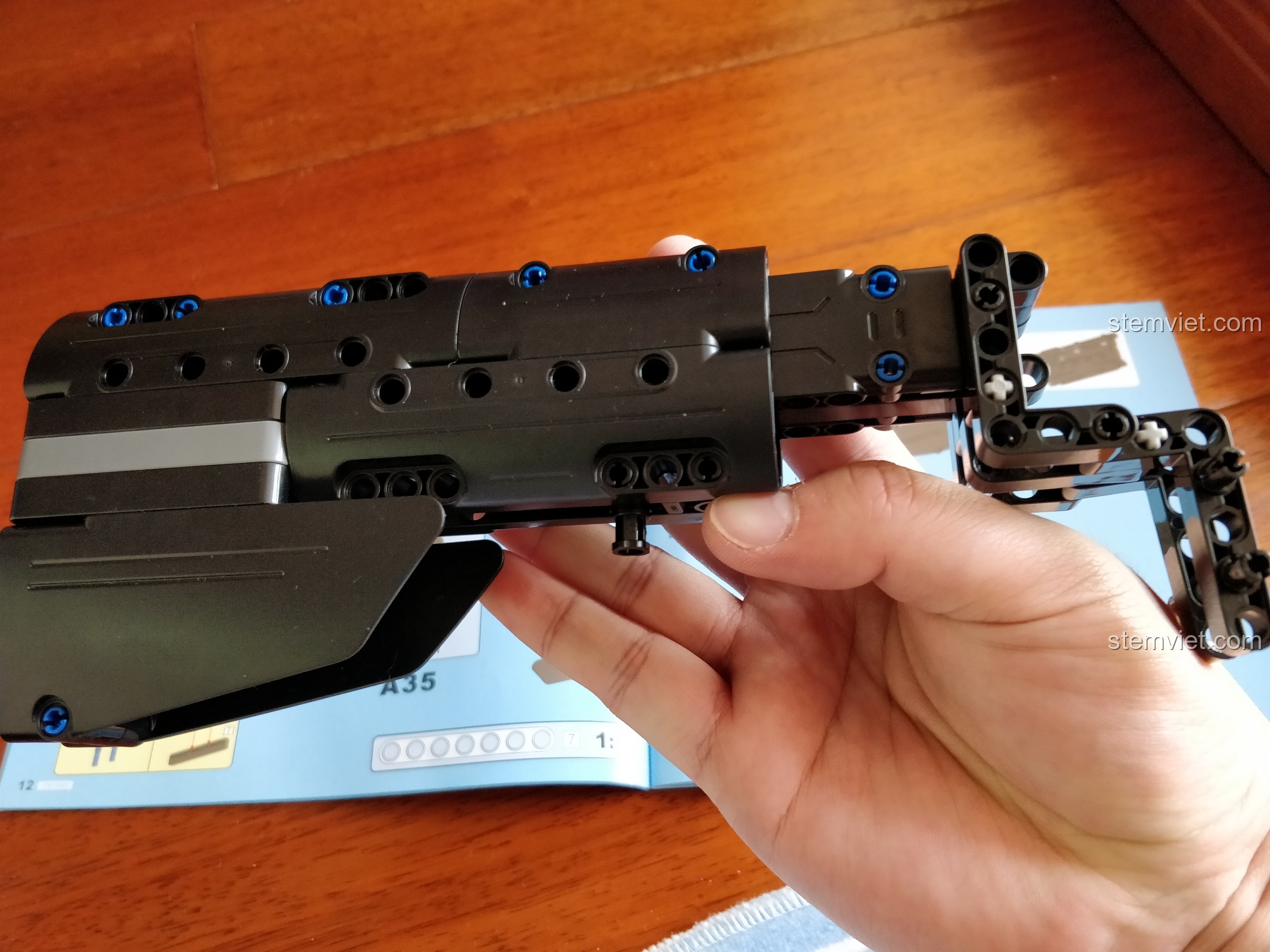 Một góc nhìn khác của báng súng đã lắp ráp, nổi bật với các chốt pin màu xanh dương trên nền đen.