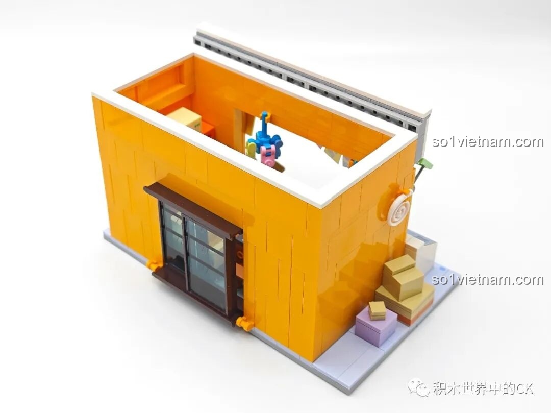 Góc nhìn từ phía sau của Tiệm Tạp Hóa Maruko, cho thấy các thùng hàng và chi tiết trang trí bên hông.