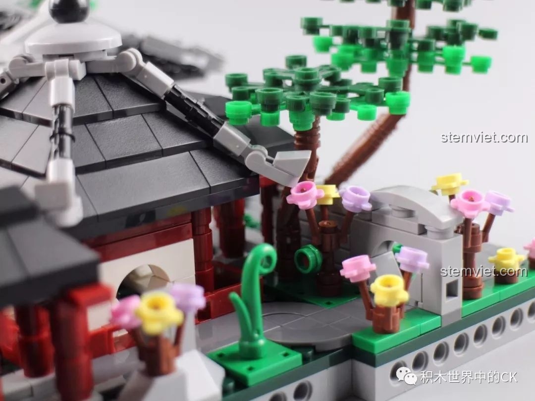 Ảnh chụp cận cảnh một góc vườn với hoa lá, cây xanh và mái đình cong của bộ Vườn Tô Châu.