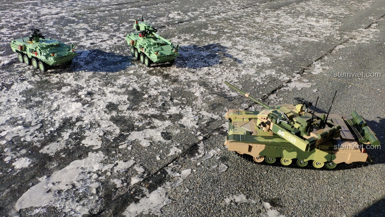 Mô hình xe tăng GUDI 6103 Xe Tăng 99A cùng hai mô hình xe quân sự khác trên nền đất đá.