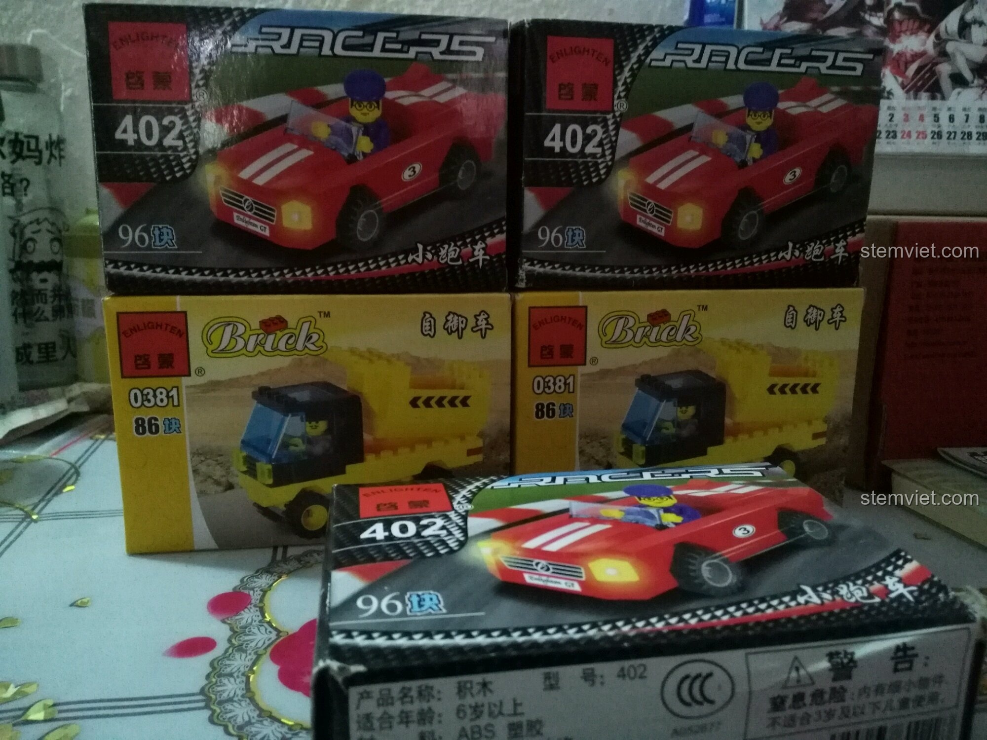 Toàn cảnh các hộp đồ chơi Enlighten 402 (xe đua đỏ) và 0381 (xe ben vàng) trên bàn.