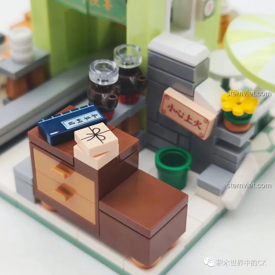 Hai mô hình Quán Trà Thảo Mộc Vương Lão Cát và xe đẩy trà cùng các nhân vật, tạo cảnh phố phường.