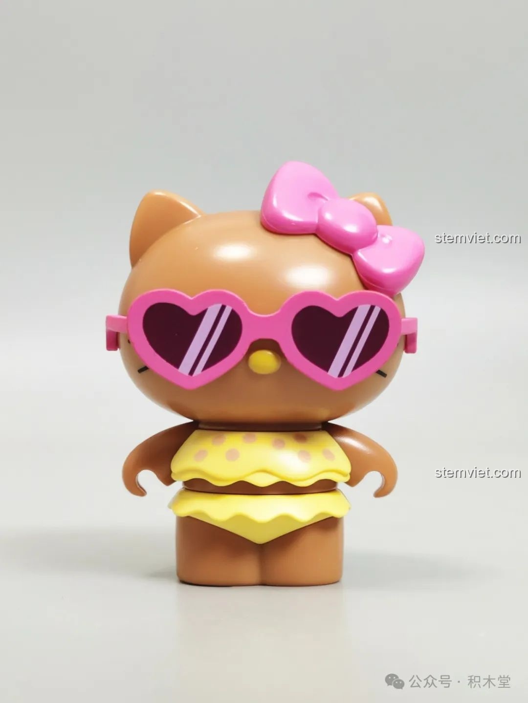 Mô hình Hello Kitty da nâu trong bộ bikini chấm bi vàng và kính râm hồng, một phần của bộ đồ chơi lắp ráp Tắm Nắng Xinh Đẹp TOP TOY.