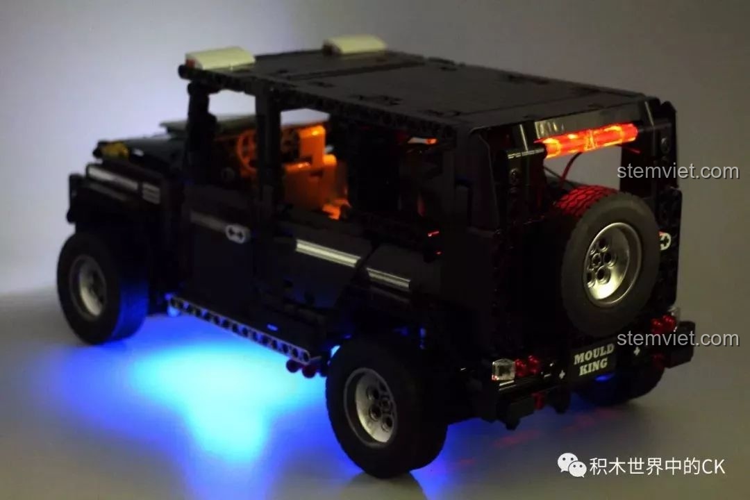 Xe Mould King 13070 G65 được bật đèn, với đèn pha sáng và đèn gầm màu xanh dương nổi bật trong bóng tối.