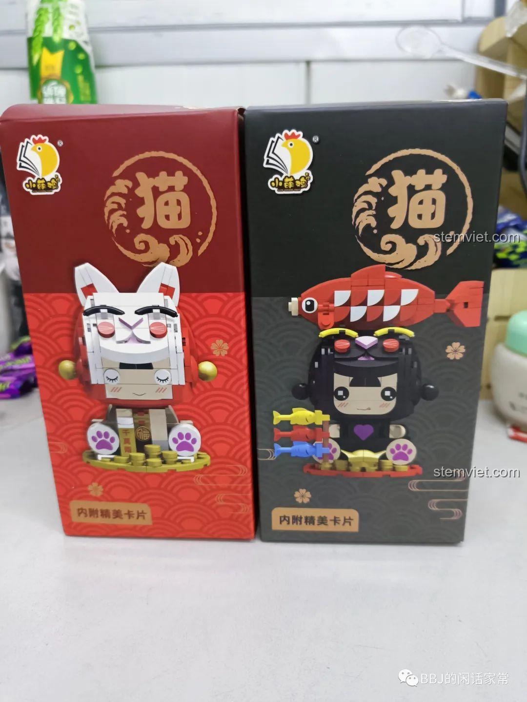 Mặt sau của hai hộp đồ chơi lắp ráp Xiao Meng Ji, hiển thị hình ảnh mô hình hoàn chỉnh của Mèo Thần Tài và Cô Bé Mèo.