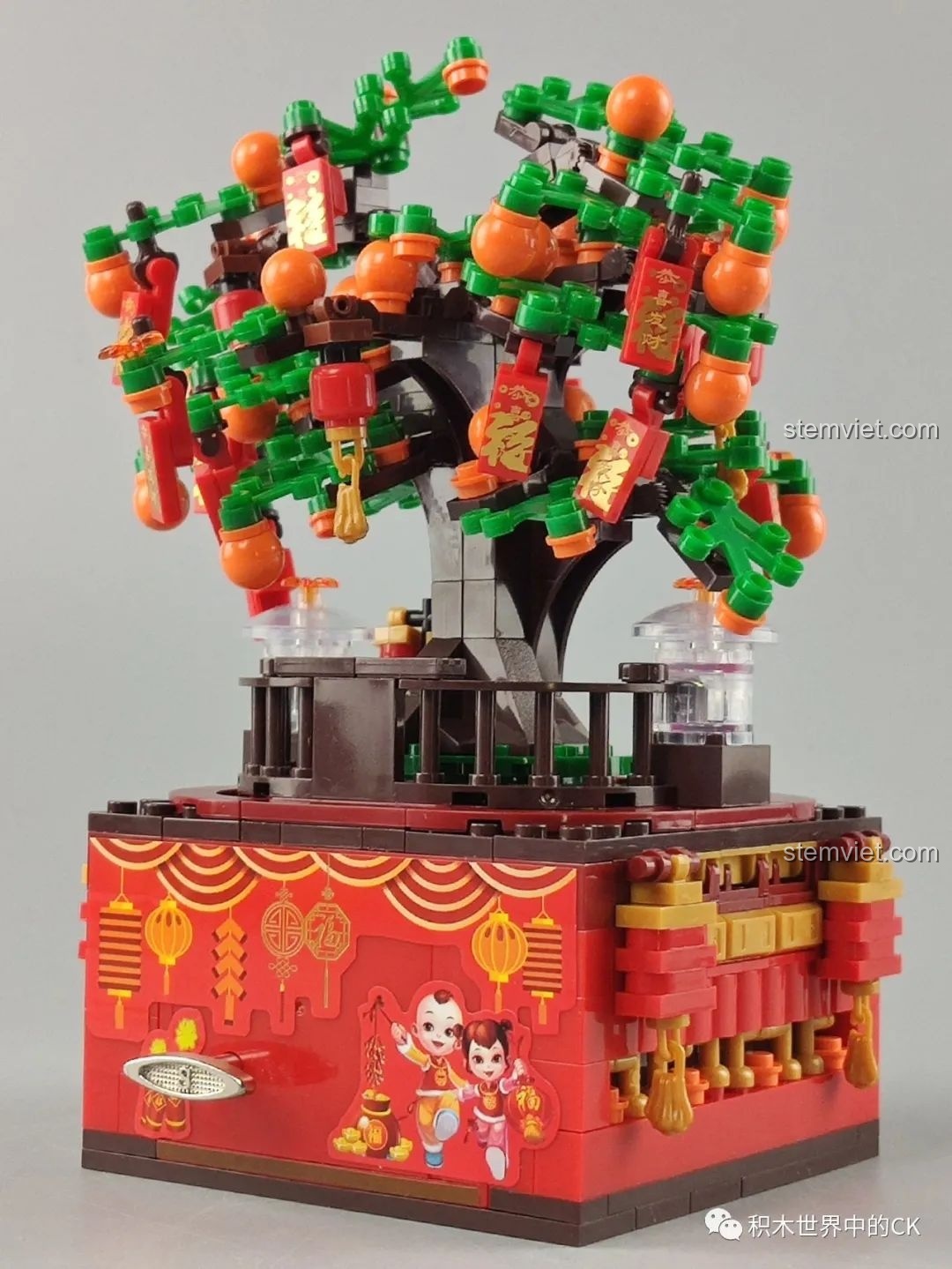 Mặt bên hộp nhạc ZHEGAO QL0987 với hình ảnh hai bé vui xuân và các chi tiết trang trí Tết.