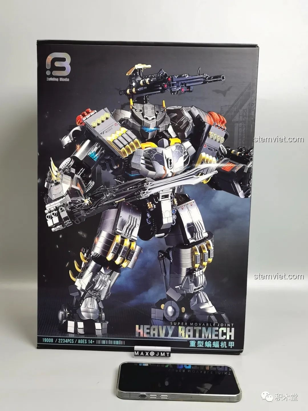 Hộp sản phẩm đồ chơi mô hình Robot Batmech Hạng Nặng Justice Buster 19008 đặt cạnh iPhone để so sánh kích thước.