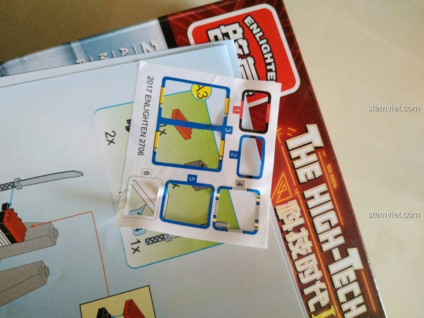 Sách hướng dẫn và sticker của bộ lắp ráp QMAN 2706 bị dính vào nhau, cần cẩn thận khi gỡ ra.