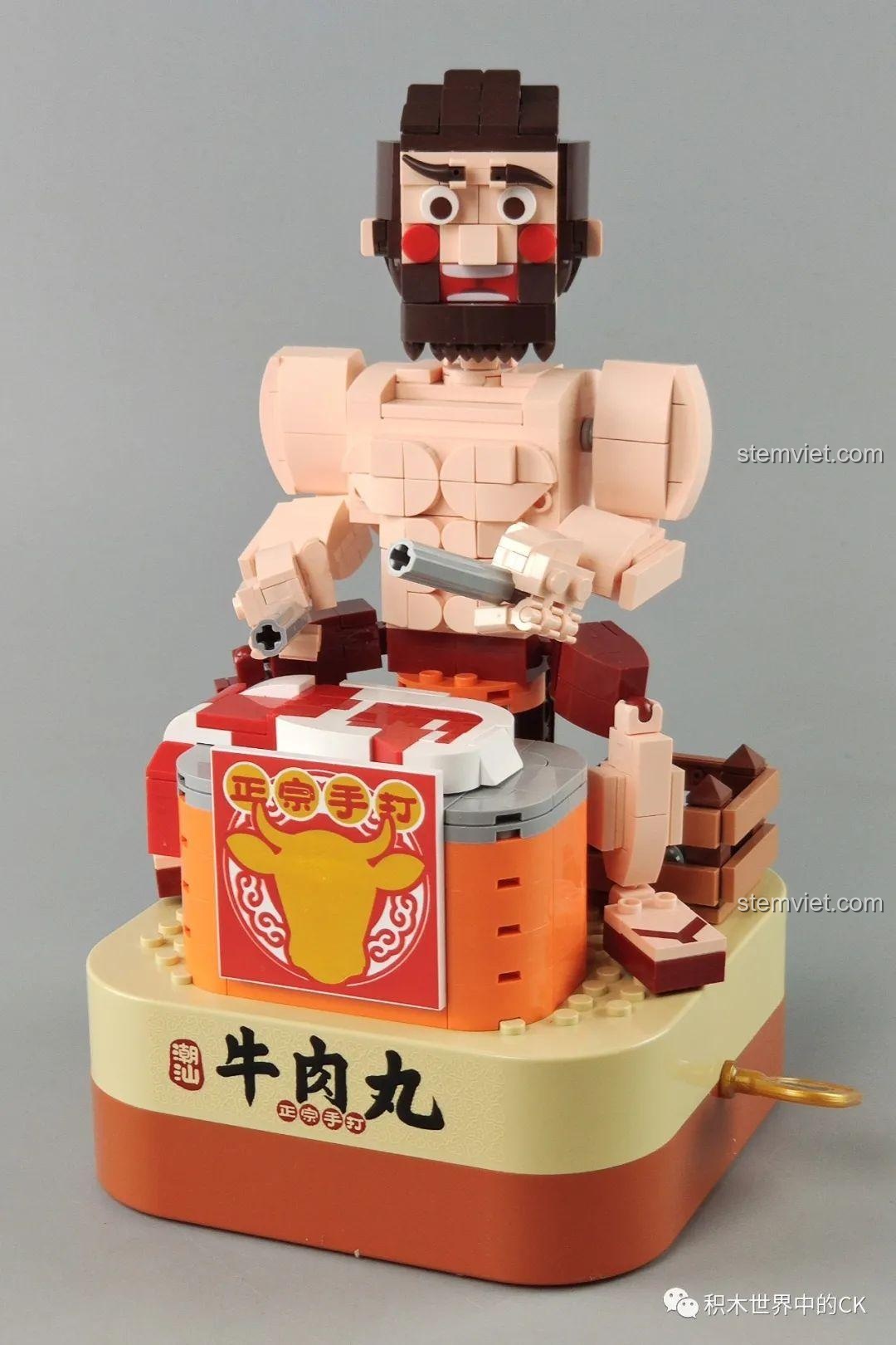 Mô hình hoàn chỉnh của bộ đồ chơi lắp ráp Hộp nhạc thịt bò viên JAKI JK1801, với người đàn ông đang đập thịt bò viên.