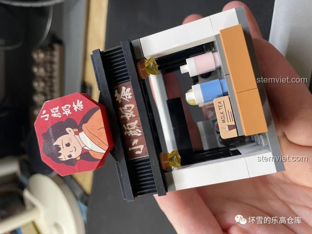 Mô hình quán Trà Sữa Tiểu Nhan JAKI JK2131 được cầm trên tay, cho thấy kích thước nhỏ gọn và dễ thương.