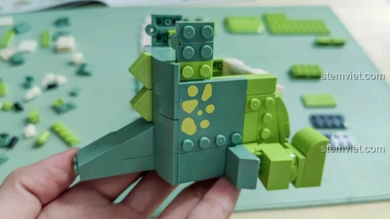 Mô hình Khủng long T-Rex đa năng JAKI JK5102 đang được lắp ráp, nhìn từ bên hông, lộ rõ họa tiết đốm.