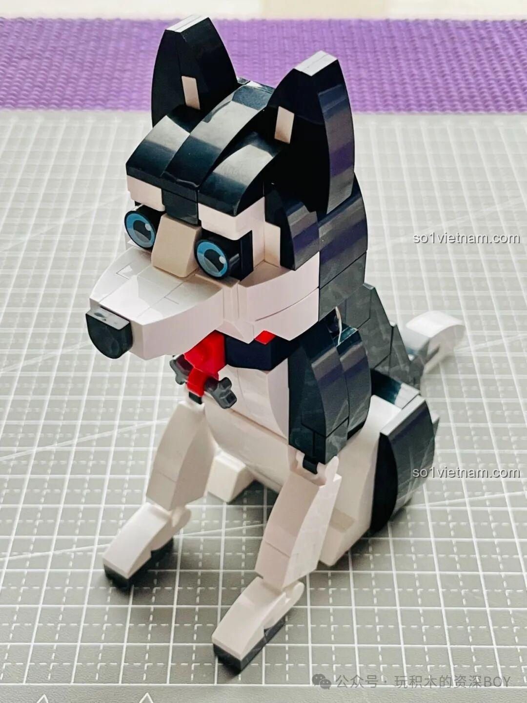 Góc nhìn nghiêng của mô hình chó Husky JAKI JK8130, khoe trọn vẻ đẹp của bộ lông đen trắng và đôi mắt xanh.