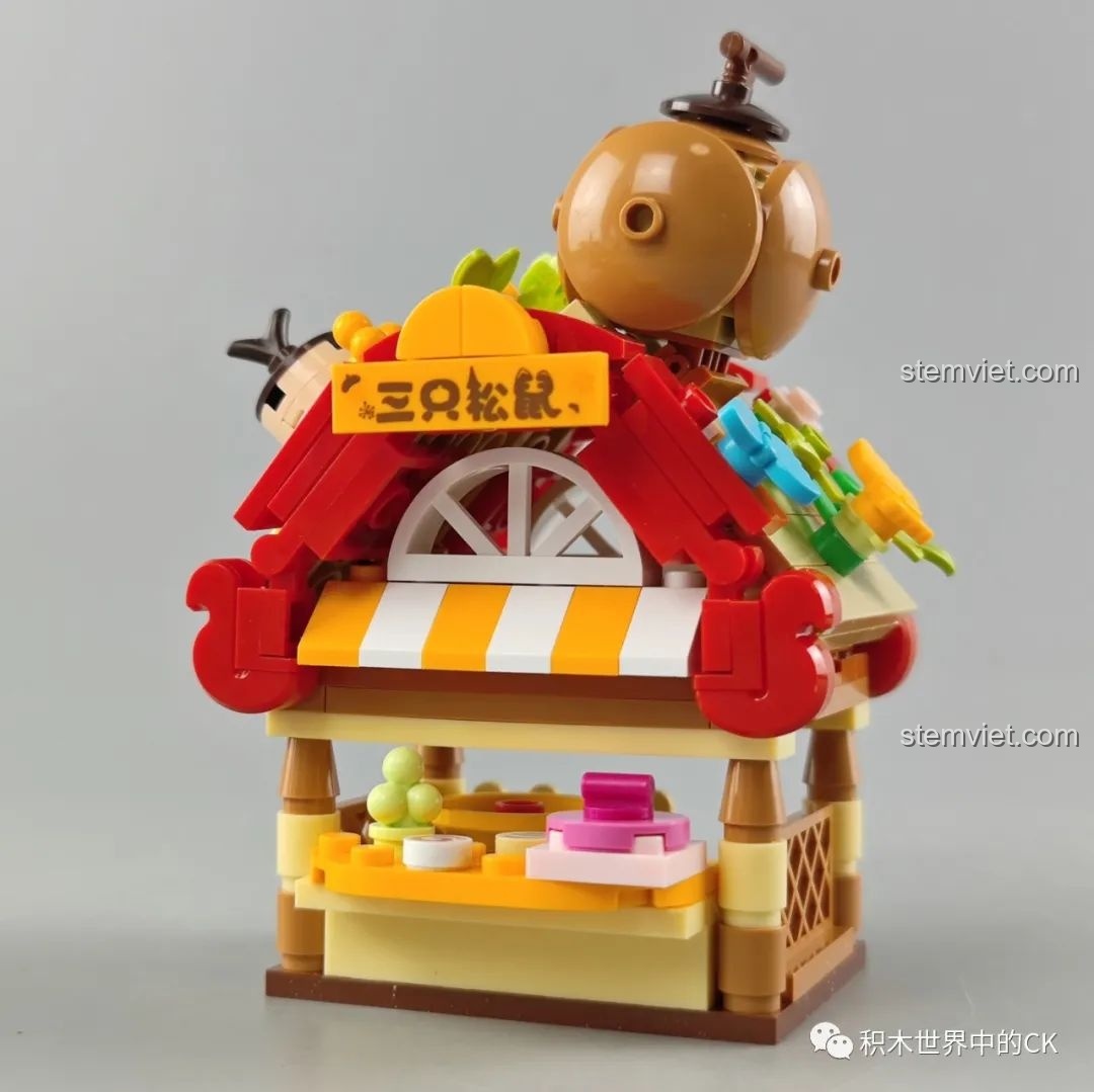 Mô hình quầy hàng hạt dẻ trong bộ lắp ráp JAKI với mái che màu đỏ, sọc vàng trắng và các chi tiết trang trí hạt dẻ trên nóc.