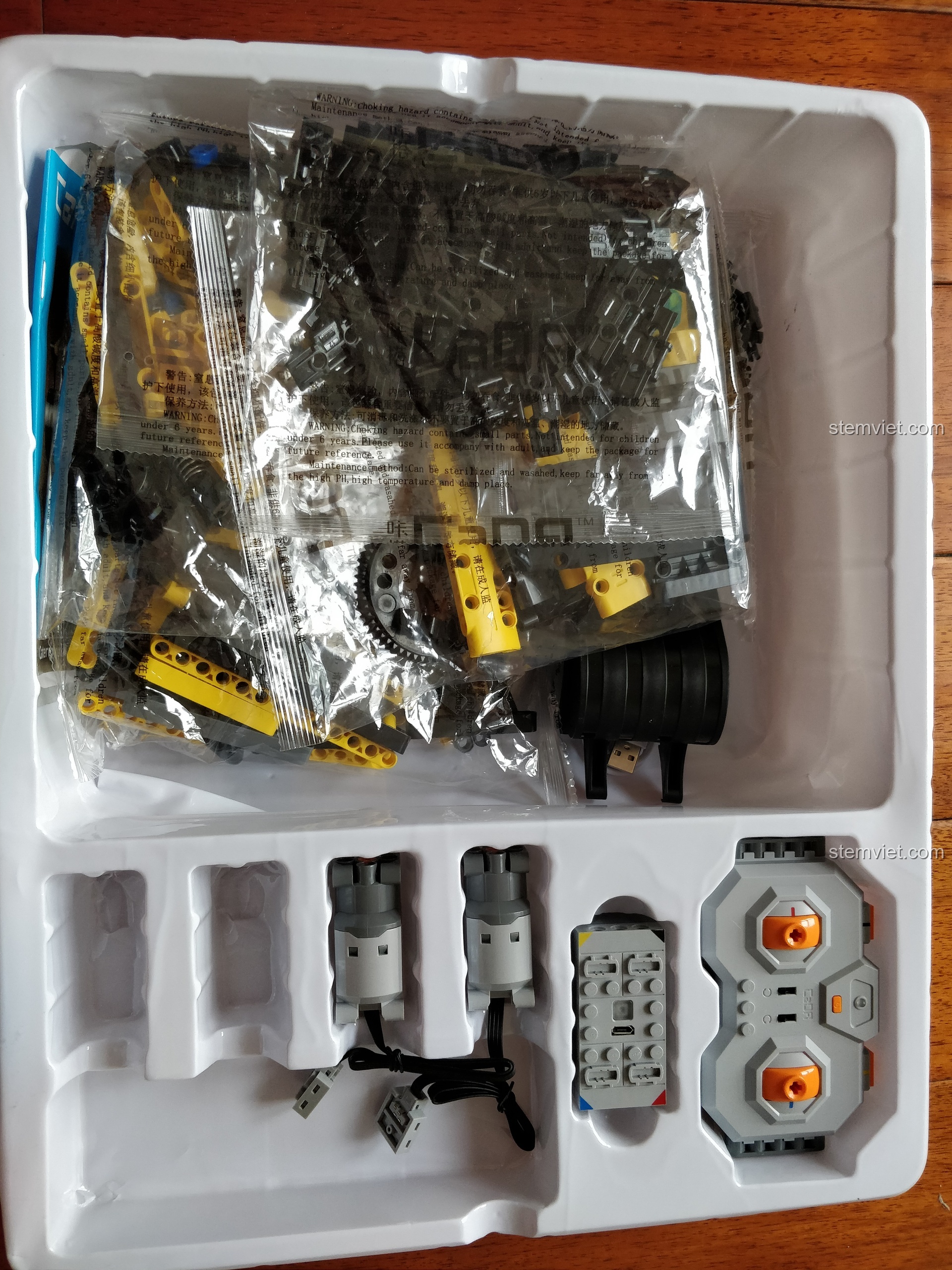 Bên trong hộp Cỗ máy công trường mạnh mẽ C51057 là khay nhựa định hình, sắp xếp các túi chi tiết và bộ điều khiển gọn gàng.