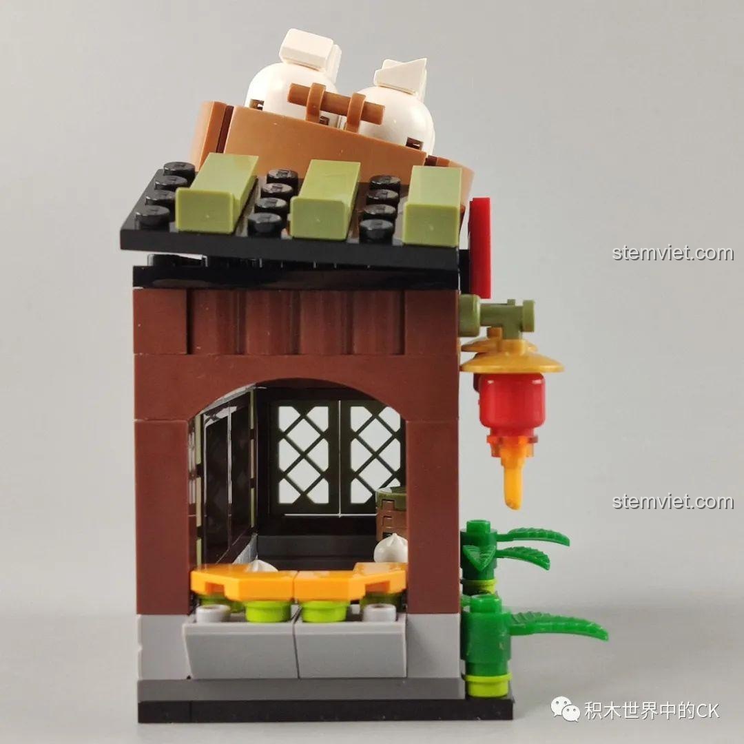 Góc nhìn bên trong mô hình Tiệm Bánh Bao Vô Song QMAN 72012, với bàn ghế và quầy bán hàng.