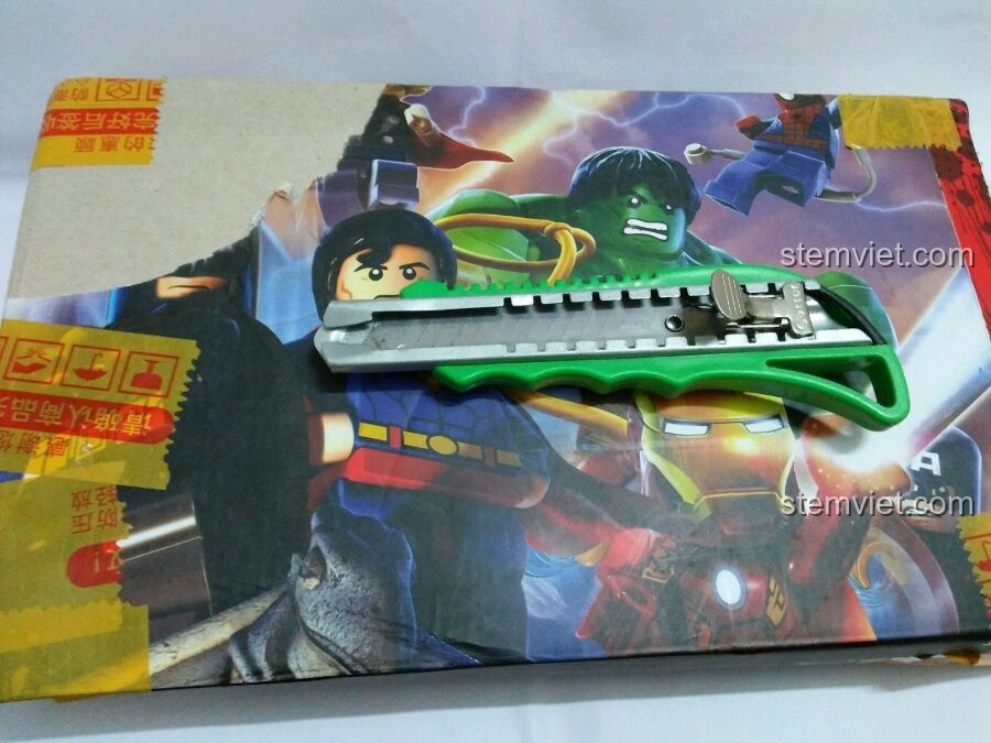 Dụng cụ khui hộp màu xanh lá cây đặt trên hộp hàng tái chế Marvel, chuẩn bị mở bộ lắp ráp Enlighten 1906.