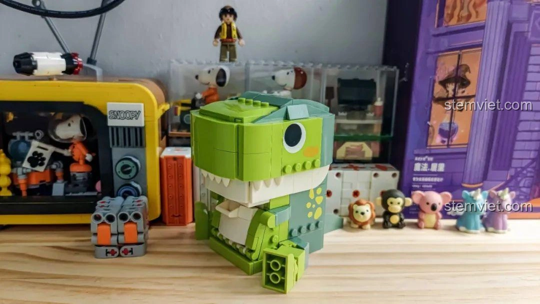 Khủng long T-Rex trong bộ JAKI JK5102 đặt trên bàn, miệng mở ra, sẵn sàng đựng đồ dùng học tập.