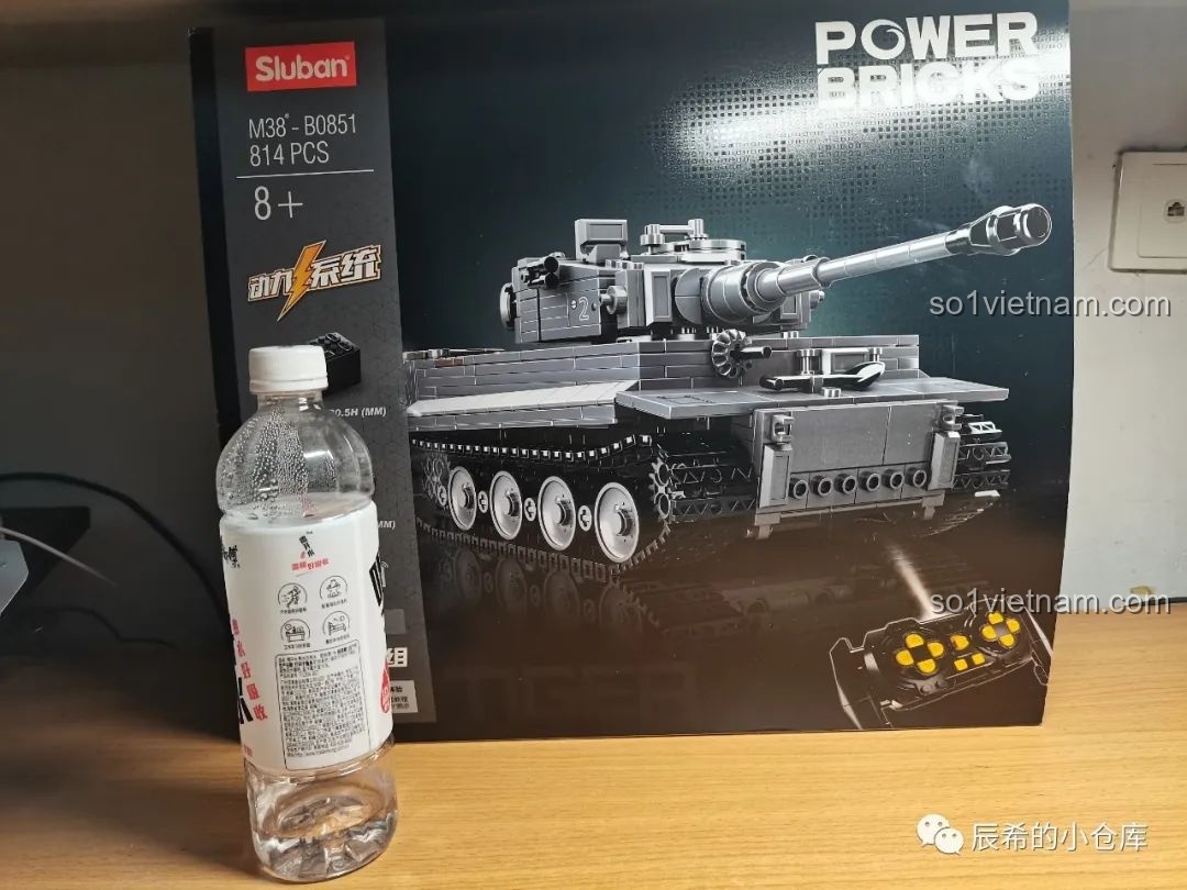 So sánh kích thước hộp bộ lắp ráp Sluban M38-B0851 với một chai nước để thấy độ lớn của sản phẩm.