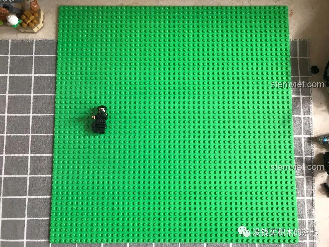 So sánh kích thước tấm đế 48x48 với một minifigure, cho thấy sự rộng lớn của bộ đồ chơi Lâu Đài Phép Thuật.