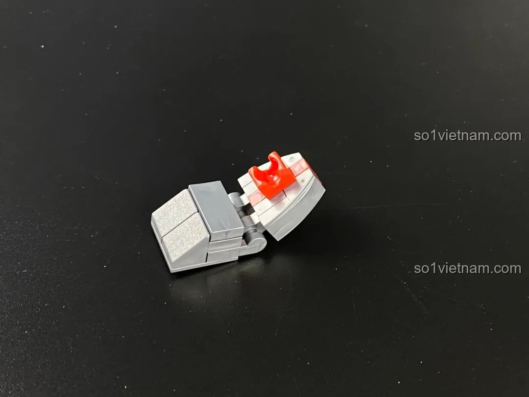 Chi tiết bàn chân của Mecha Geed đang được lắp ráp, với các mảnh màu xám và đỏ.