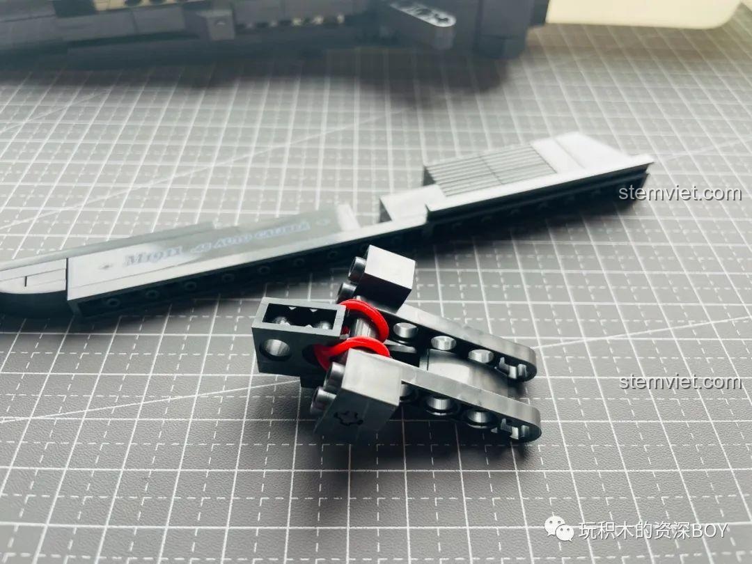 Các bộ phận của cơ chế trượt và nạp đạn PanlosBrick 670007 M1911 đang được lắp ráp, tạo tính năng động.