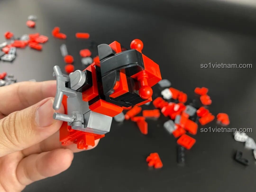 Quá trình lắp ráp phần lưng của Mecha Geed, các chi tiết màu đỏ, đen và xám được ghép lại.