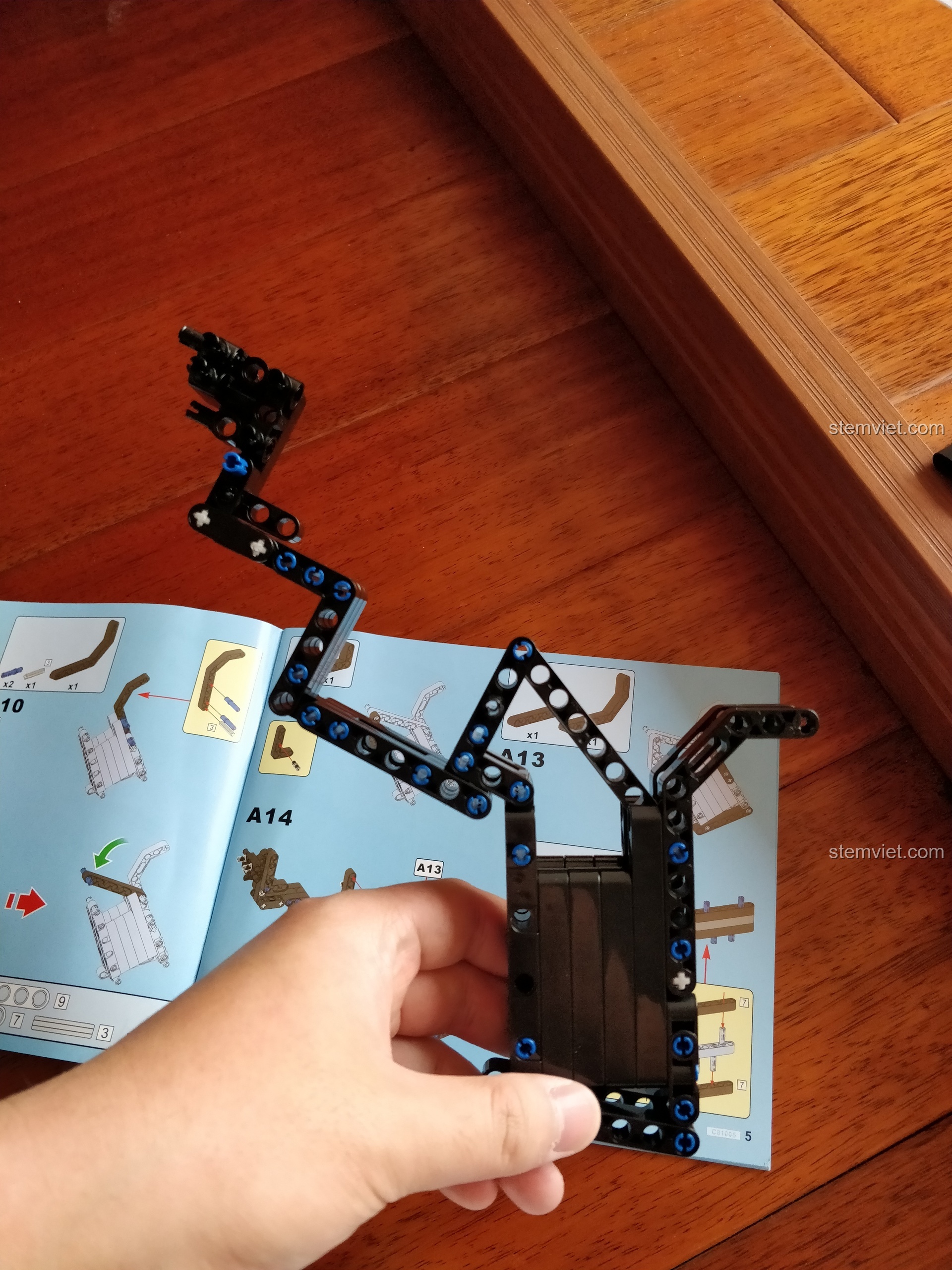 Tay người chơi đang lắp ráp phần khung và tay cầm của bộ đồ chơi mô hình Súng M4A1 CaDA theo hướng dẫn.