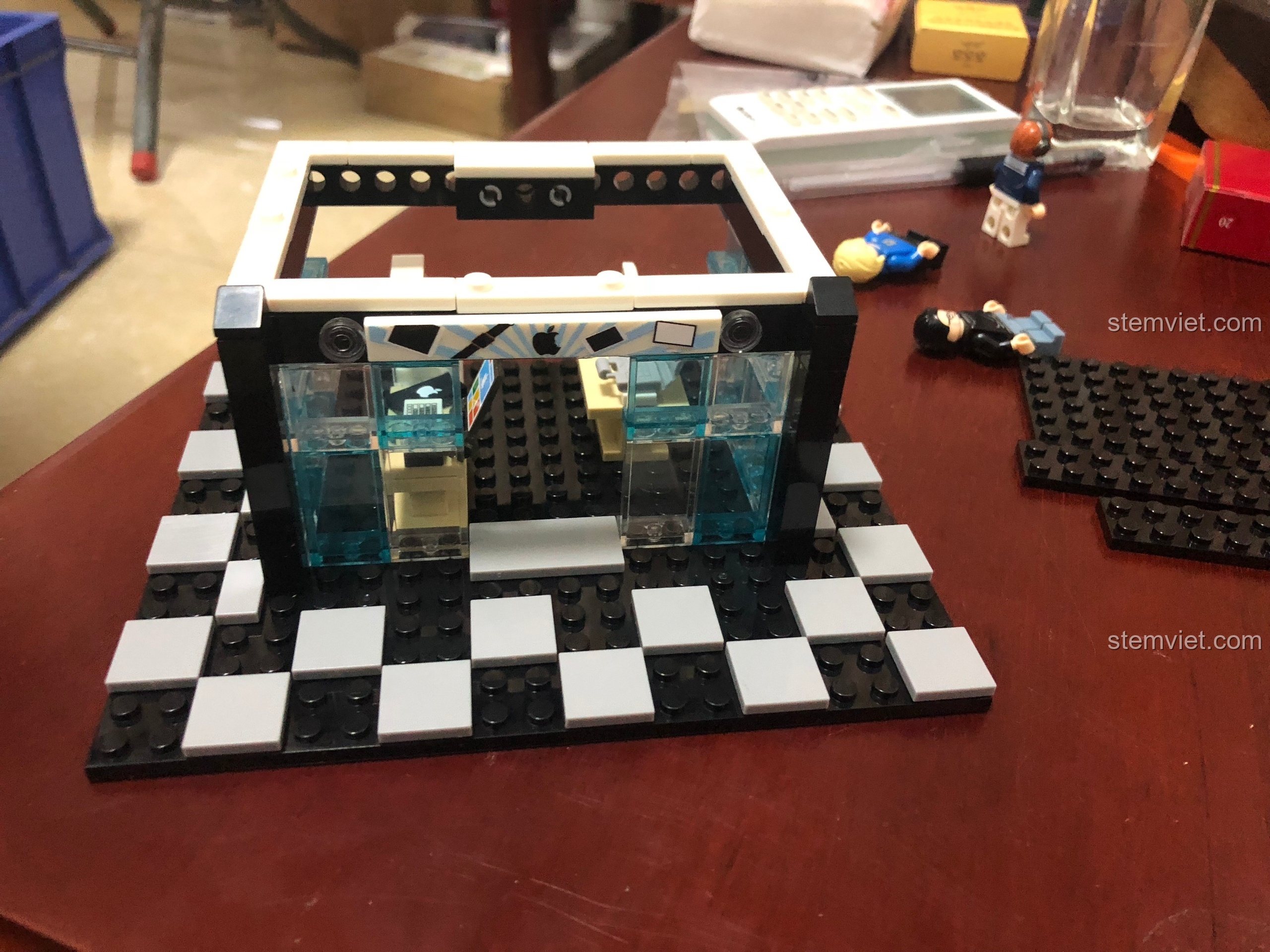 Mô hình cửa hàng công nghệ Sembo 601020 với các bức tường kính màu xanh đang được lắp ráp.