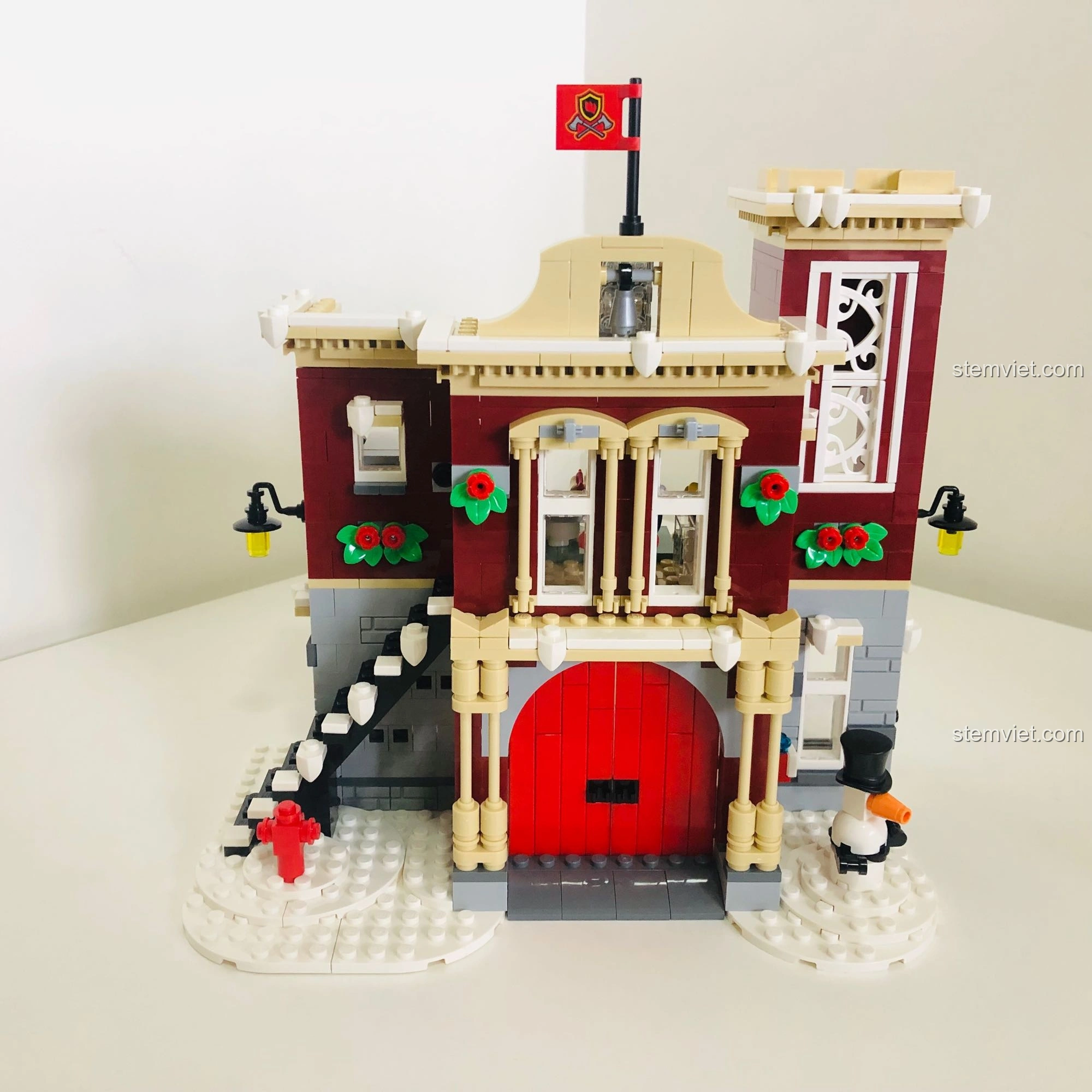 Mặt tiền trạm cứu hỏa LEGO 10263 Winter Fire Station với màu đỏ, xám và be kết hợp hài hòa, cửa lớn và trang trí Giáng Sinh.