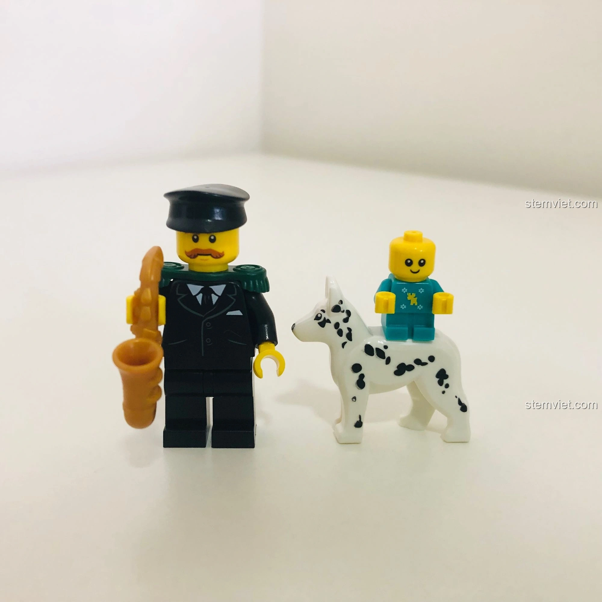 Cận cảnh nhân vật ông lão chơi saxophone với cầu vai xanh lá và em bé mặc áo len tuần lộc trong LEGO 10263.