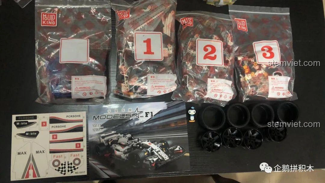 Toàn bộ linh kiện của bộ lắp ráp Mould King 13117 F1 Xe Đua, bao gồm túi chi tiết, sách hướng dẫn, sticker và bánh xe.